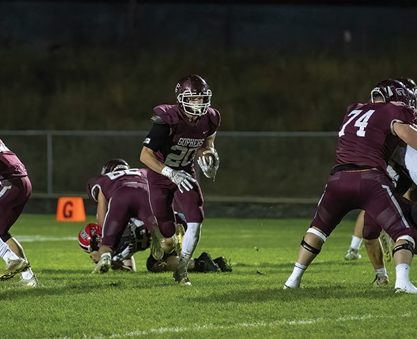 Chatfield’s Ben Carrier runs through a gaping void as lineman Mitchel Hinckley (background) and Jake Stevens (right) dominate blocks while Ethan Eickhoff (left) is also shown. Carrier ran for 208 yards and three scores as the #2 Gophers pounded #8 Cannon Falls 40-8 to clinch their third Southeast-White title in four years. Photo by Leif Erickson