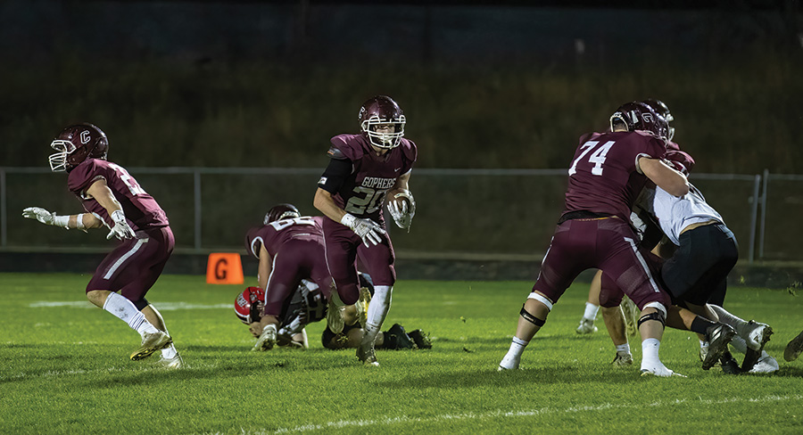 Chatfield’s Ben Carrier runs through a gaping void as lineman Mitchel Hinckley (background) and Jake Stevens (right) dominate blocks while Ethan Eickhoff (left) is also shown. Carrier ran for 208 yards and three scores as the #2 Gophers pounded #8 Cannon Falls 40-8 to clinch their third Southeast-White title in four years. Photo by Leif Erickson