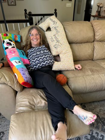 Holly appreciated the items others shared with her and now wants to pass on those items to others who could use them. Here she poses with the three breast cancer pillows that helped her after her surgery. Photo by Wanda Hanson