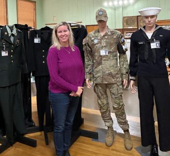 Michelle Hoskins poses next to her son Tyler Groth’s contribution to the armed forces display. Photo by Wanda Hanson