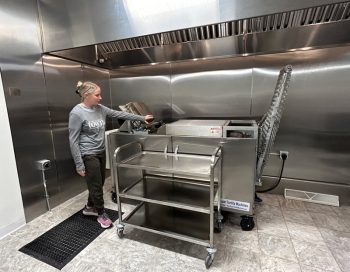 Anna demonstrates how the press and lefse baking machine works. Photo by Wanda Hanson