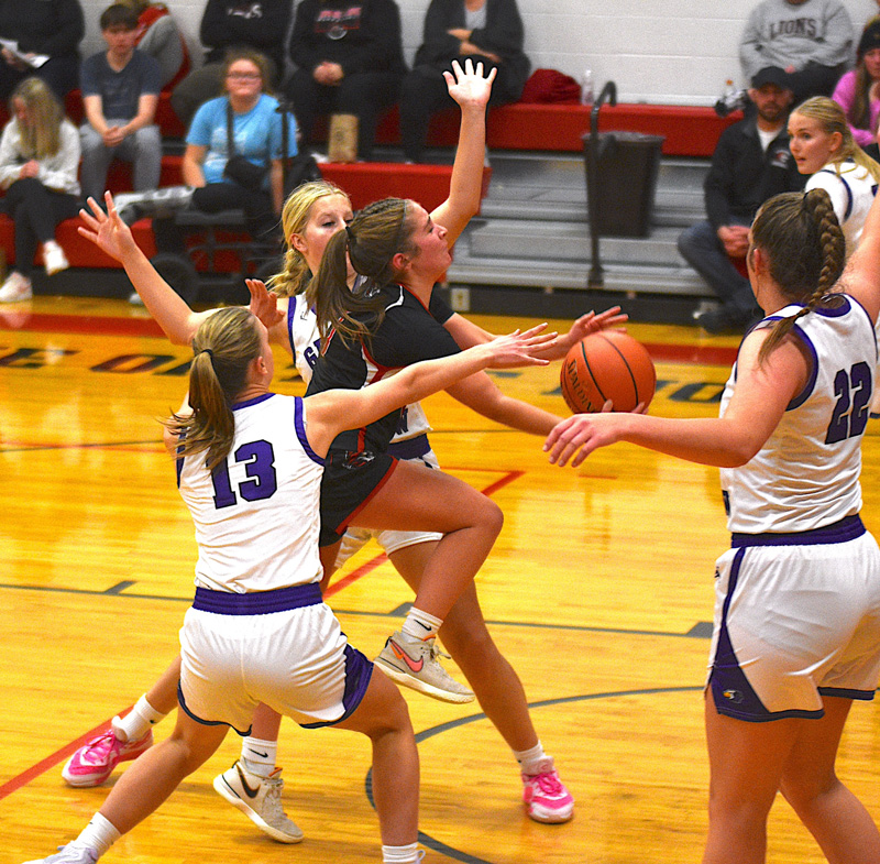 Spring Grove point guard Siri Konkel slices through the Grand Meadow defense to score with an underhanded scoop shot. Defending for the Superlarks are (#13) Alyssa Peterson, Aspen Kolling and (#22) Rylee Schaufler. Konkel scored seven points and passed out a game-high seven assists as the Lions turned away the Superlarks in an early Southeast Conference showdown. Photo by Lee Epps