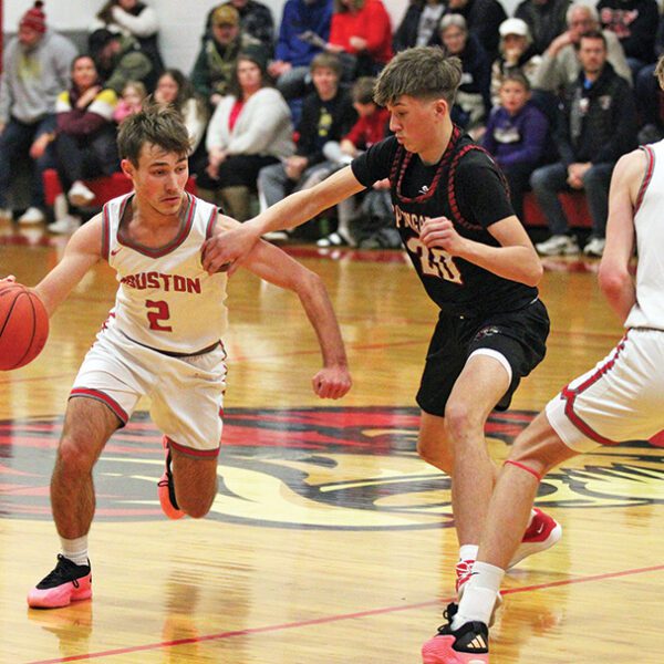 Spring Grove’s Lyric Stadtler (#20) tries to stay with Houston’s Zach Olson and the upcoming screen from Carter Geiwitz. The SEC-East leading Hurricanes (5-1, 7-2) topped the Lions 55-46 in overtime to sweep the season series. Photo by Paul Trende