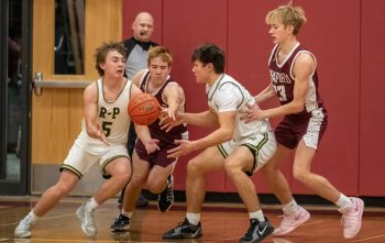 Rushford-Peterson’s Cayden Lea takes the hand-off from teammate Zach Baker while Chatfield’s Ross Stoehr and Keyan Danninger defend. The #7 in Class A Trojans blew open a 31-27 halftime lead, prevailing 77-52 over the Gophers for R-P’s fourth straight win. Photo by Leif Erickson