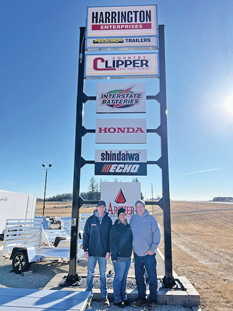 Celebrating 25 years of success, Harrington Enterprises owners Chad and Camri Harrington, along with their son Carter, stand proudly beneath their business sign – a symbol of their dedication to family, hard work and customer service. Photo submitted