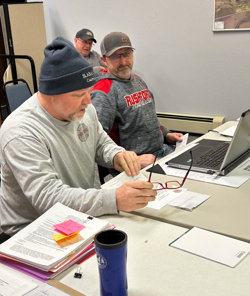 Retiring Fire Chief Chad Rasmussen, left, and the new fire chief, Nick Smith report to the council. Dave Lombard from Public Works is in the background. Photo by Wanda Hanson