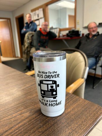 The coffee mug says it all with humor. Owner Garrett Regan, Manager Todd Kiehne and Travis Willford are in the background. Photo by Wanda Hanson
