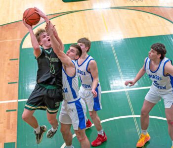 Rushford-Peterson’s Carson Johnson hangs for a shot over Mabel-Canton’s Tyler Larson in the teams’ 1A Round of 16 contest. The Trojans finished the first half on a 31-0 run to help post an 81-33 victory. Photo by Dawn Hauge