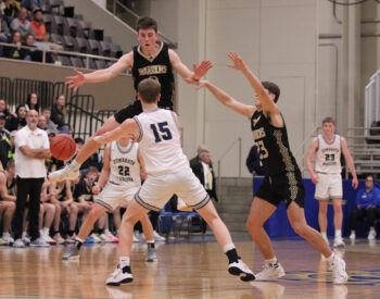 Caledonia’s Ben Stemper (airborne) and Coby Hammell defend Zumbrota-Mazeppa’s Cooper Meyers in the teams’ 1AA semifinal. The #3 in AA Warriors forced 28 turnovers versus the Cougars and posted a 71-48 win to move on to the section finals. Photo by Paul Trende