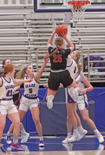 Spring Grove/Mabel-Canton’s Kinley Soiney rises for a shot surrounded by Grand Meadow defenders, notably Lauren Queensland (right) and Aspen Kolling (left). Symbolic of the 1A semifinal game, there were typically Larks warding off a Lion path to the basket as GM prevailed 60-39 to make the 1A finals. Photo by Paul Trende