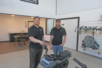 Thor Alexander, general manager, and James Hagen, owner of Total Powersports, standing with an electric dirt bike they sell. Photo by Sara York