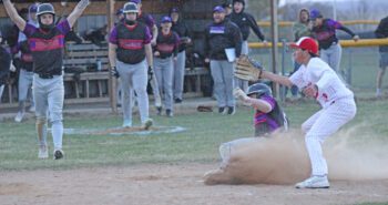 GMLOK’s Sam Howard scores the game-winning run on a wild pitch, with Hurricane Asher Semling covering home plate, and Bulldog Parker Johnson arms raised in the background. GMLOK trailed 16-7 in the game, but came back to win 17-16 in walk-off fashion. Photo by Paul Trende