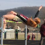 Chatfield’s Jaelyn LaPlante slips over the bar in the High Jump as her coach Jeff DeBuhr looks on in the background. LaPlante leapt 5’0” to take first in the event while also finishing second in the 100-meters. Photo by Paul Trende