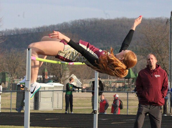 Chatfield’s Jaelyn LaPlante slips over the bar in the High Jump as her coach Jeff DeBuhr looks on in the background. LaPlante leapt 5’0” to take first in the event while also finishing second in the 100-meters. Photo by Paul Trende