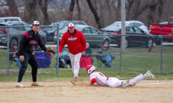 Houston’s Ryan Riederer slides safely into third base as Alden-Conger/Glenville-Emmons’ third baseman and Hurricane coach Jason Carrier look on. Houston baseball (4-1) had a crazy start to the year, winning its first four games by shutout, then falling 16-14 to Medford. Photo by Emma Geiwtiz