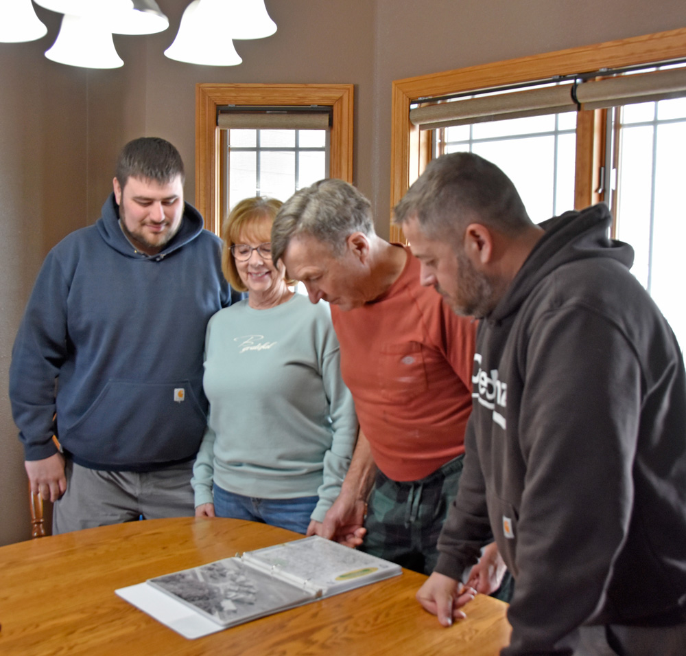 From left to right, Cody Erickson with his grandma and grandpa Sharon and Dean Wissing and his dad Brian Erickson enjoy reflecting on their family’s past as they browse through the family scrapbook. Photo by Charlene Corson Selbee