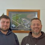 Cody and his dad Brian Erickson. Behind them is a photo of the family farm. Photo by Charlene Corson Selbee