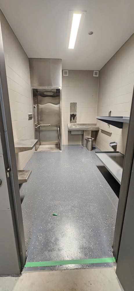 A view of a new, handicap accessible jail cell. The table has one seat installed and one open area for a wheelchair. Also note the roll-in shower with flip-down seat and easy access to the sink. Photo by Ellen Whalen