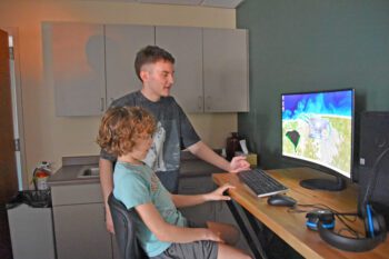 Jacob Hernandez assists Spring Grove student Jaxon VanMinsel with digital support. Photo by Charlene Corson Selbee
