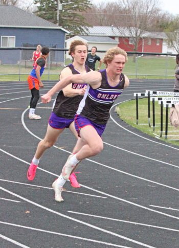 Kaleb Yunker and Zach Reiland perform the last exchange of the boys 4x100 at the GMLOKS track and field meet. Said team took first (and Reiland also swept top billing in both hurdle events) as the Bulldog boys won their third team title of the year. Photo by Paul Trende