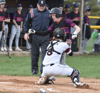 GMLOK runner Caden Reiter is tagged out at home plate by Spring Grove catcher Ezra Griffin during the first inning of the teams’ SEC contest. Reiter was injured on the play and did not return in a game where the Bulldogs led 1-0 and had the Lions down to their final out, only for SG to win 8-2 in eight innings. Photo by Lee Epps