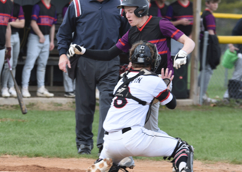 GMLOK runner Caden Reiter is tagged out at home plate by Spring Grove catcher Ezra Griffin during the first inning of the teams’ SEC contest. Reiter was injured on the play and did not return in a game where the Bulldogs led 1-0 and had the Lions down to their final out, only for SG to win 8-2 in eight innings. Photo by Lee Epps