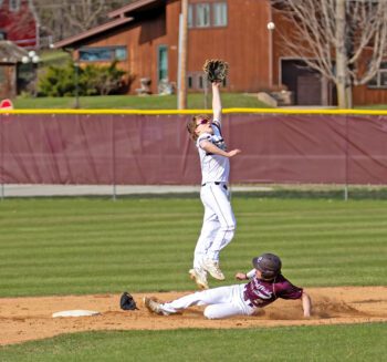 Caledonia’s Tanner Ginther leaps for a high throw to second base as Chatfield’s Kaisen Johnson slides in safely. The Warriors won the game 5-4 in eight innings on a Ben Stemper RBI-double. Photo by Leif Erickson