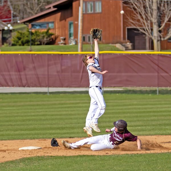 Caledonia’s Tanner Ginther leaps for a high throw to second base as Chatfield’s Kaisen Johnson slides in safely. The Warriors won the game 5-4 in eight innings on a Ben Stemper RBI-double. Photo by Leif Erickson