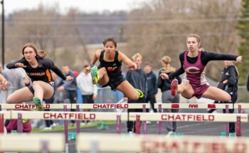 St. Charles’ Lydia Warmkagathe, LFCMC’s Ava Jacobsen, and Chatfield’s Rebecca Copeman clear the first hurdle near simultaneously at Chatfield’s home meet. Copeman won the 100-meter hurdle event. Photo by Leif Erickson
