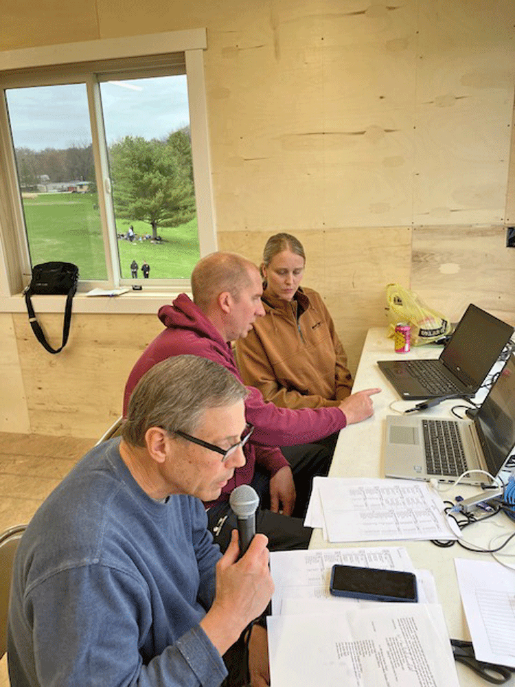 Seen in the new press box are Randy Paulson, announcer and Jeff Debuhr, head track coach explaining the duties of timing to Sarah Thieke. Photo by Mary Allen