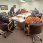 Eitzen City Council members examine architectural drawings for the proposed community center remodel. From left to right: Mitch Lange, Mayor Jeff Adamson (standing), Matt Sauer of Custom Homes of Eitzen, City Clerk Steve Schuldt, Emily Burrichter and Doug Meyer. Photo by Charlene Corson Selbee