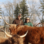 Mark and Jamie Schulz standing with one of their favorite Highland cows, Rosie. Photo by Kirsten Zoellner