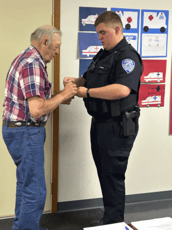 Charlie Chapel prepares to pin the badge on his grandson, Curtis Chapel. Photo by Wanda Hanson