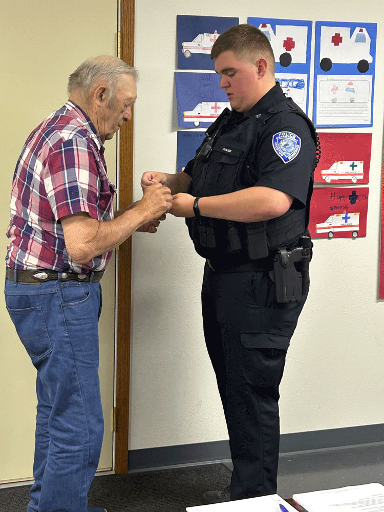 Charlie Chapel prepares to pin the badge on his grandson, Curtis Chapel. Photo by Wanda Hanson
