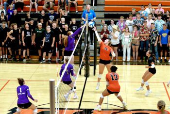 With each team’s student section, and other players, looking on, Grand Meadow’s Gracie Foster (left) and Lanesboro’s Jensyn Storhoff (right) vie for the ball at the net in the teams’ notable season-opening SEC battle, a 3-1 Lark victory. Photo by Craig Johnson