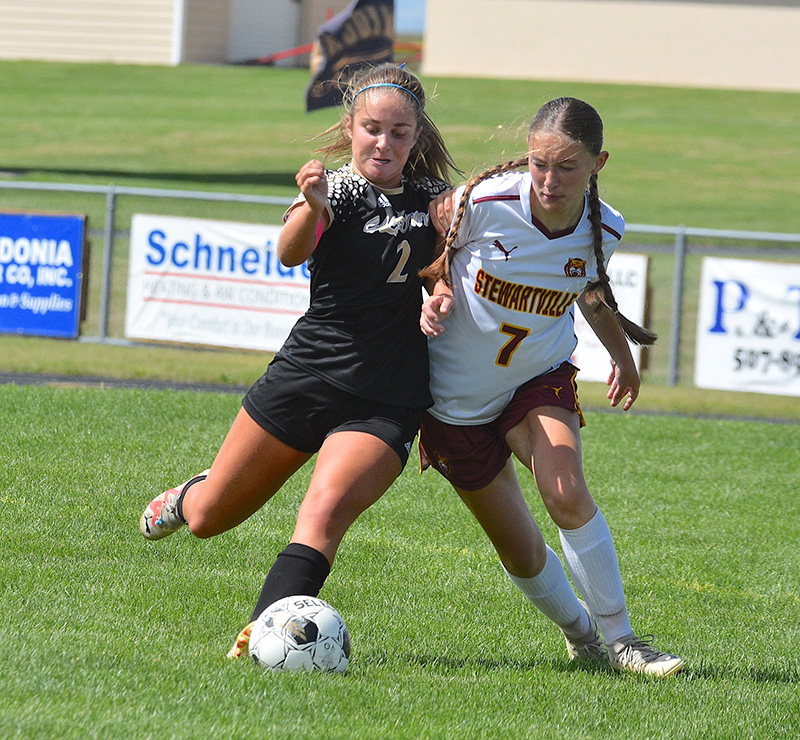 Siri Konkel (left) of Caledonia/Spring Grove/Houston contends for possession with Stewartville’s Jesica Eden. The Warrior midfielder/forward scored once and assisted on two other goals as the Warriors blanked the Tigers, 3-0. Photo by Lee Epps