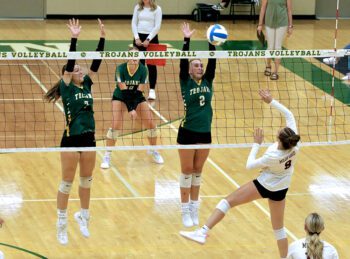 Rushford-Peterson defenders Shelby Tesch (left) and Torryn Schneider (right) throw up a double-block versus the attack of Medford’s Jayden Schweisthal in the teams’ season-opener, a Trojan 3-0 win. Photo by Craig Johnson