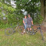 Carin Hyter and Josh Jacobson pose with their bikes and their team mascot, their dog Harlow. Photo by Wanda Hanson