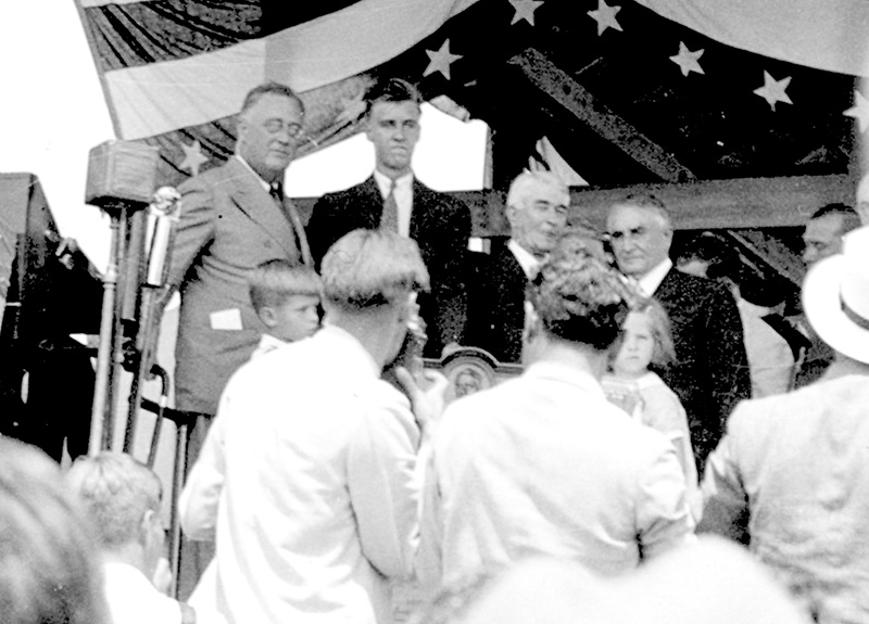 On the podium, August 8, 1934, at Soldier Field in Rochester, Minn., were, from left, President Franklin Delano Roosevelt, his 18-year-old son John Aspinwall Roosevelt, Dr. William Mayo and Dr. Charles Mayo. Broadcast nationwide on radio, FDR delivered a speech honoring the Mayo brothers and their medical clinic. Note the disabled president grasping a brace for support. Photo courtesy of the Houston County Historical Society