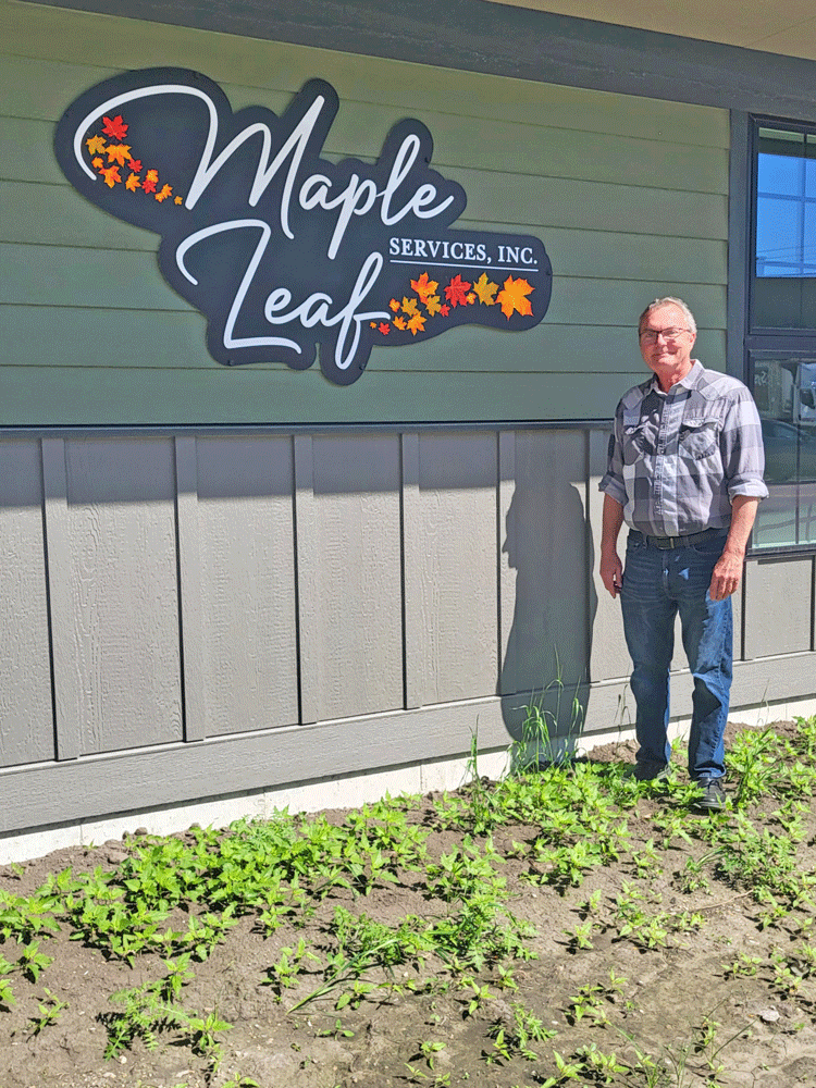Dean Aug stands by the new Maple Leaf Services sign on the beautiful new building in Preston.