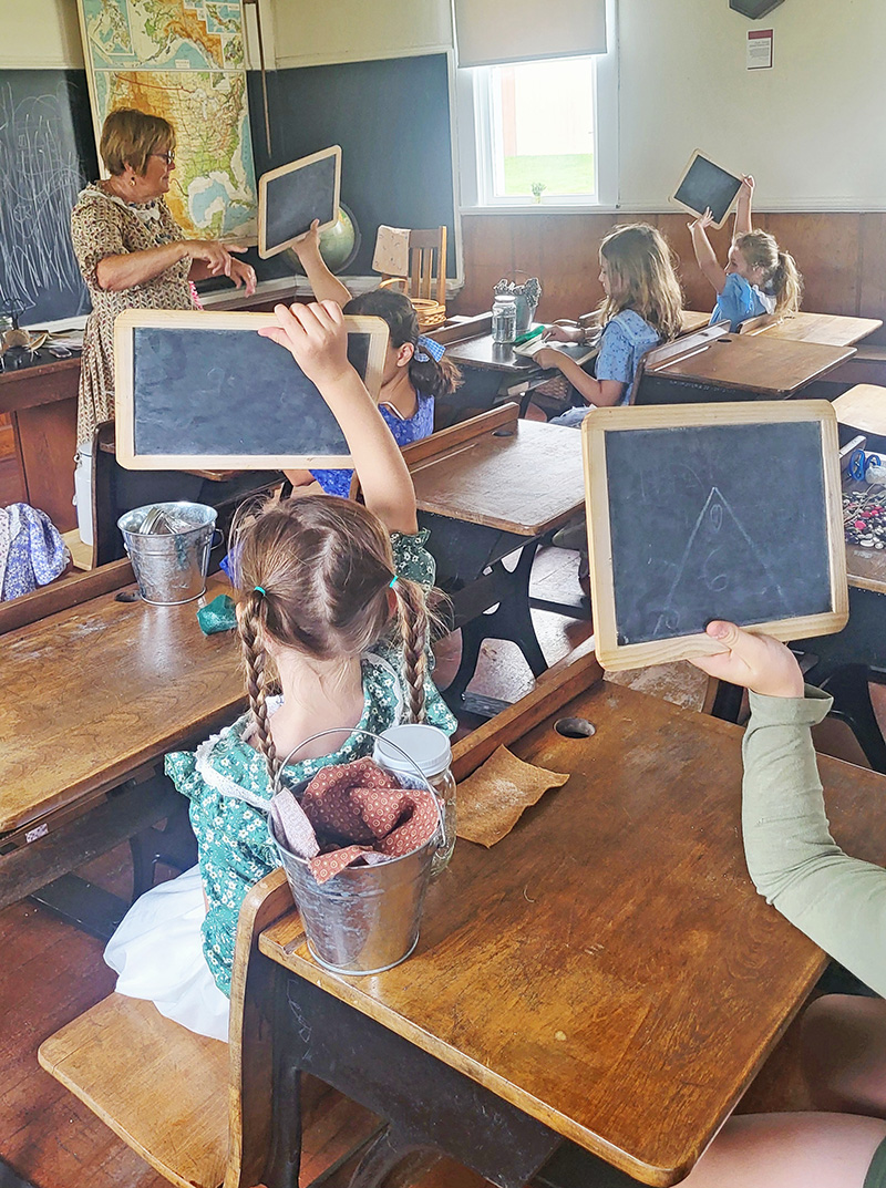 Students hold up their slates after answering a question. Photo by Hannah Wingert