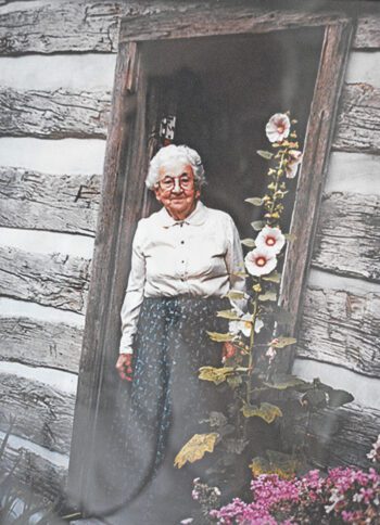 Ragnhild St. Mary stands in the doorway of the 1880 Pioneer Log Cabin, where she demonstrated spinning wool for more than three decades at the Houston County Fair. Photo courtesy of the Houston County Historical Society