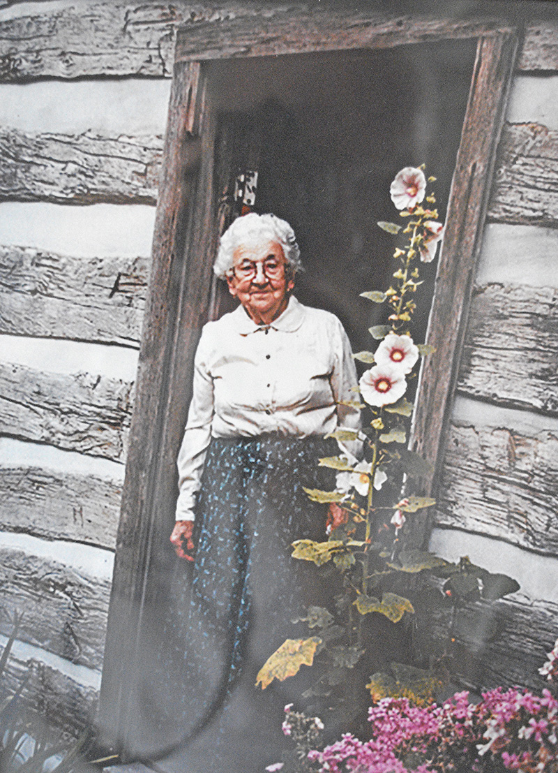 Ragnhild St. Mary stands in the doorway of the 1880 Pioneer Log Cabin, where she demonstrated spinning wool for more than three decades at the Houston County Fair. Photo courtesy of the Houston County Historical Society