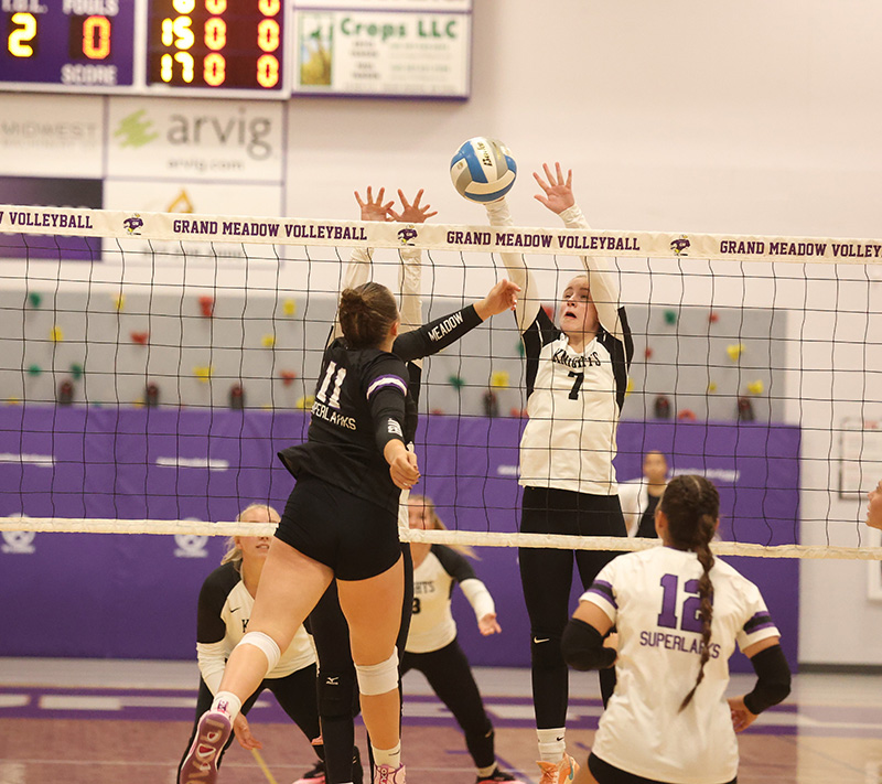 Grand Meadow’s Holly Weiss (near #11) and Kingsland’s Sydney Wendt (far #7) vie at the net for the ball in the teams’ SEC matchup, a 3-0 Lark sweep. Photo by Christine Vreeman