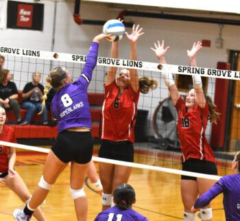 Grand Meadow’s Kendall Jack hammers a shot into the double block of Spring Grove defenders Kylie Hammell (left) and Jada Strinmoen (right). The Larks downed the Lions 3-1 to snap a 10-match series losing streak. GM (5-0, 9-4) leads the SEC-West over Southland (5-1, 5-1). Photo by Lee Epps