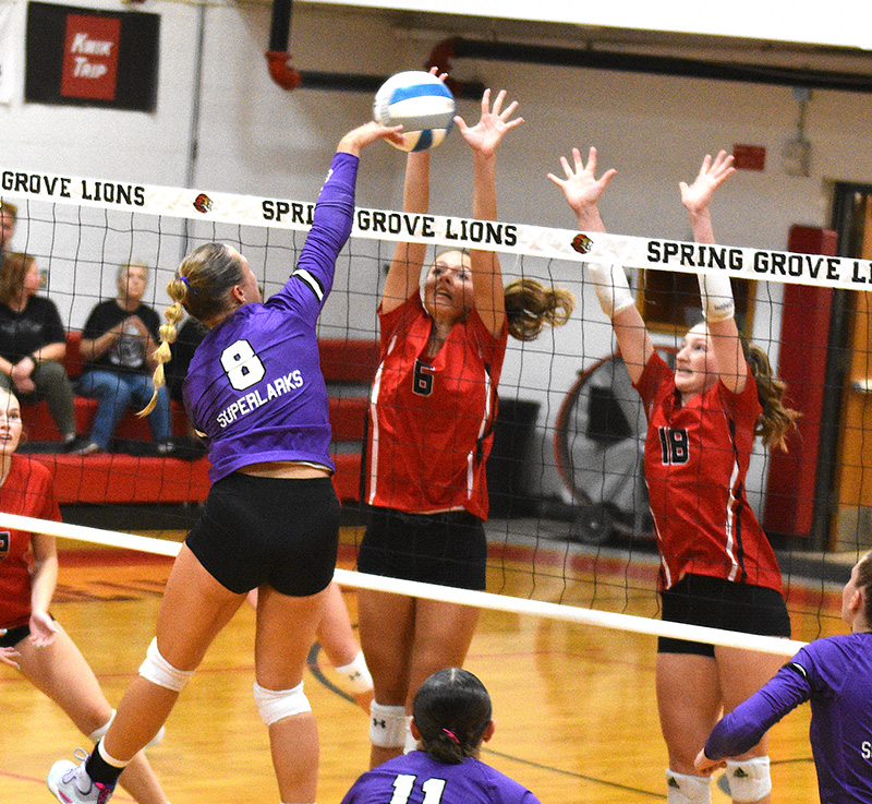 Grand Meadow’s Kendall Jack hammers a shot into the double block of Spring Grove defenders Kylie Hammell (left) and Jada Strinmoen (right). The Larks downed the Lions 3-1 to snap a 10-match series losing streak. GM (5-0, 9-4) leads the SEC-West over Southland (5-1, 5-1). Photo by Lee Epps