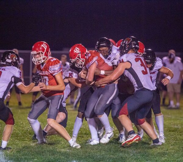 Houston’s Elliot Frauenkron battles forward against the Spring Grove defenders including Christian Bjerke (#34), Caden Gerard (#15), and others. Houston ended a 20-game losing streak to the Lions via a 24-18 victory. Photo by Emma Geiwitz