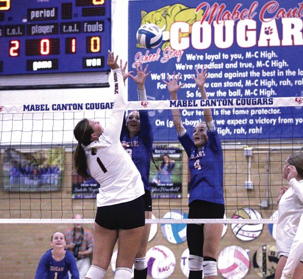 Spring Grove’s Brinley Middendorf challenges the Mabel-Canton double-block of Ella Halverson (left) and Braylee Stortz (right) in the team’s rivalry SEC match-up. The Cougars took the first two sets, but had to stave off SG’s comeback upset bid in five games (25-22, 25-17, 19-25, 19-25, 15-11), in the process continuing M-C’s 211 game SEC-match win streak. Photo by Paul Trende