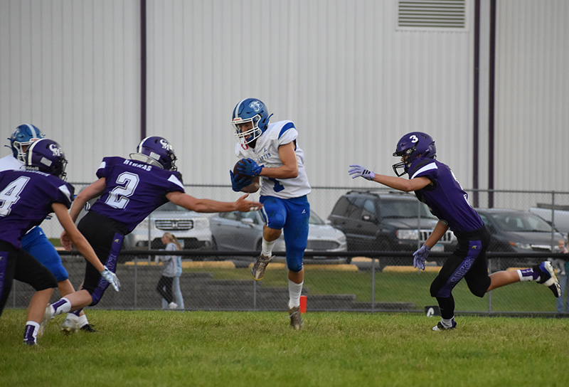 Grand Meadow defenders Brady Hyrkas (#2) and Blake Hubbard (#3) converge on Mabel-Canton’s Kale Tollefsrud in the teams’ South-East season-opening game. Leading 12-10 at the half, the Cougars used a 22-point third quarter to pull away from the Larks for a 34-18 victory. Photo by Heather Kleiboer