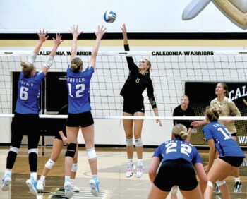 Caledonia’s Kensey King attacks over Cotter defenders Camrie Macal (#6) and Alayna Hardy (#12). The #3 in AA Warriors avenged a pair of losses to the #9 in AA Ramblers last year via a key 3-1 win. The Warriors (6-0, 15-3) lead the TRC with Fillmore Central (5-0, 13-4). Photo by Craig Johnson